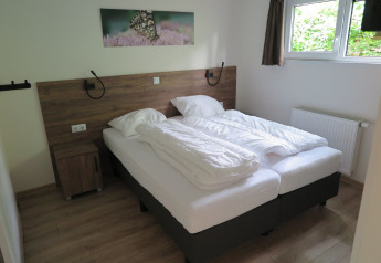 Bedroom with two single beds, white bedding, wooden floor, window, and butterfly painting on the wall.