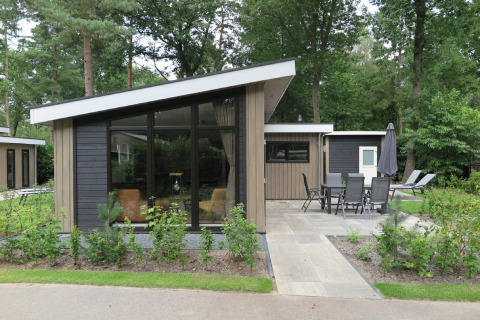 Lodge moderne au Holiday Park De Rimboe & De Woeste Hoogte 25, avec terrasse et vue sur la forêt.