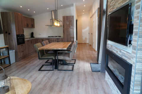 Moderne lodge i Holiday Park De Rimboe & De Woeste Hoogte 25 med åbent køkken, spisebord og pejs.
