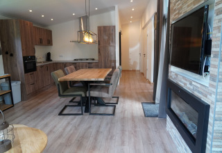 Modern lodge at Holiday Park De Rimboe & De Woeste Hoogte 25 with open kitchen, dining area and fireplace.