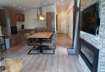 Modern lodge at Holiday Park De Rimboe & De Woeste Hoogte 25 with open kitchen, dining area and fireplace.