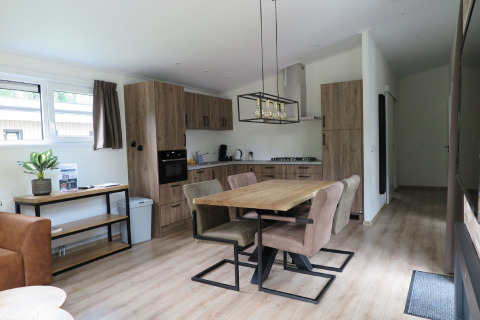 Moderne lodgekøkken og spisestue med træmøbler i Holiday Park De Rimboe & De Woeste Hoogte, Holland.