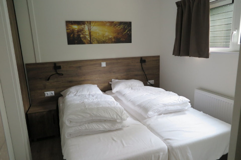 Moderne lodge soveværelse på Holiday Park «De Rimboe & De Woeste Hoogte 25» i Holland med to enkeltsenge.