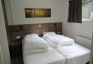 Moderne lodge soveværelse på Holiday Park «De Rimboe & De Woeste Hoogte 25» i Holland med to enkeltsenge.