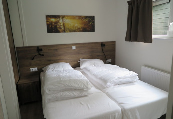 Modern lodge bedroom with two single beds at Holiday Park «De Rimboe & De Woeste Hoogte 25» in the Netherlands.