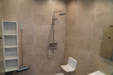 Bathroom with shower, fold-down seat, shelves, and floor squeegee at Holiday Park De Rimboe & De Woeste Hoogte 25.