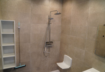 Bathroom with shower, fold-down seat, shelves, and floor squeegee at Holiday Park De Rimboe & De Woeste Hoogte 25.