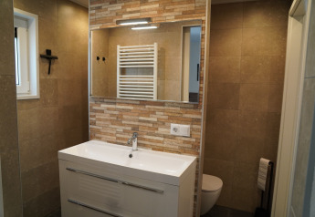 Modern bathroom at Holiday Park De Rimboe with mirror, white sink, beige tiles, and wall-mounted towel rack.