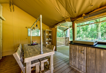 Interno di una tenda safari al Country Estate Gerner 8 nei Paesi Bassi, con arredi rustici in legno.