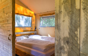 Cozy bedroom with double bed and rustic wood walls in a safari tent at Country Estate «Gerner 8», Netherlands.