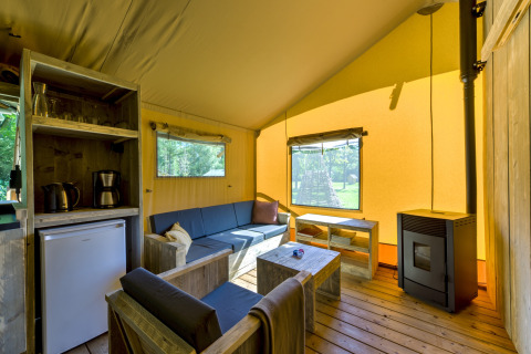 Cozy safari tent interior at Country Estate Gerner 8, Netherlands, featuring wood furniture and a stove.