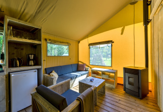 Cozy safari tent interior at Country Estate Gerner 8, Netherlands, featuring wood furniture and a stove.