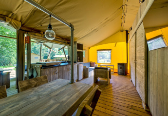 Interno di una tenda safari al Country Estate Gerner 8 nei Paesi Bassi, arredato con mobili rustici in legno e colori caldi.