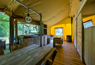 Interior of a safari tent at Country Estate Gerner 8 in the Netherlands, featuring rustic wood furniture and bright decor.