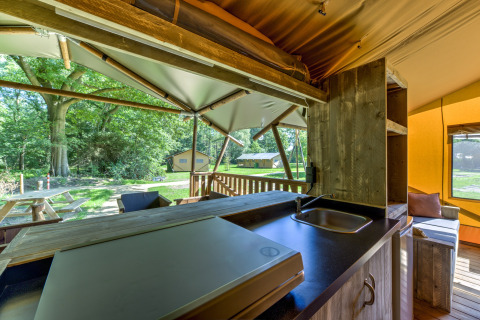 View from a safari tent kitchen at Country Estate Gerner 8, featuring a terrace and lush green outdoors.