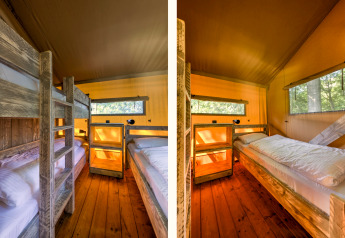 Zona notte in una tenda safari al Country Estate Gerner 8 nei Paesi Bassi con letti a castello e legno.