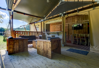 Safari tent Country Estate ‘Gerner 8’ with wooden furniture and covered terrace in the Netherlands.
