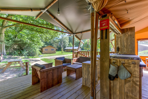 Outdoor lounge area of a safari tent at Country Estate Gerner 8, Netherlands, with wooden furniture.