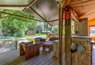 Buitenlounge van een safaritent op Country Estate Gerner 8, Nederland, voorzien van houten meubilair.