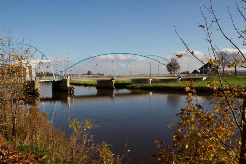 View of a modern bridge over a calm river near Country Estate Gerner 8, surrounded by autumn trees in the Netherlands.