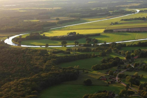 Aerial view of lush fields, winding river, and woods at Country Estate “Gerner 8” in the Netherlands.