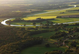 Aerial view of lush fields, winding river, and woods at Country Estate “Gerner 8” in the Netherlands.