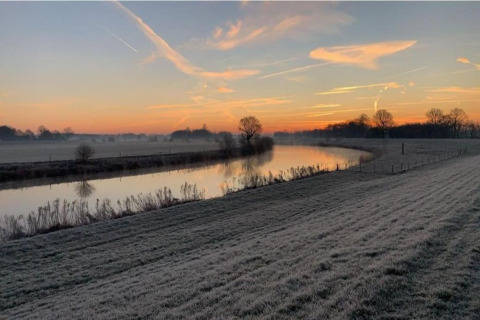 Sonnenaufgang über einer frostigen Wiese und einem ruhigen Fluss bei Country Estate Gerner 8 in Holland.