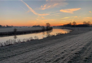 Sunrise over a frosty field and calm river at Country Estate Gerner 8 in the Netherlands, scenic view.