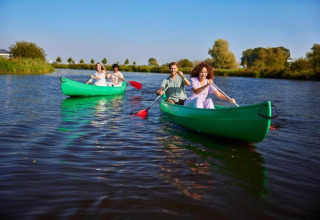 Four people paddling two green canoes on a lake at Country Estate Gerner 8, Netherlands, on a sunny day.