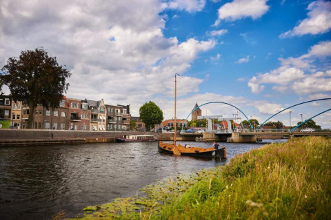 River scene with boats, houses and a modern bridge near Country Estate Gerner 8, Netherlands, cloudy sky.