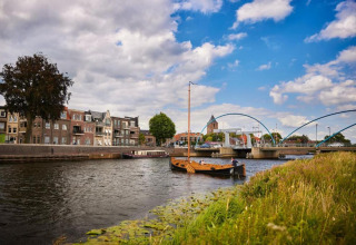 River scene with boats, houses and a modern bridge near Country Estate Gerner 8, Netherlands, cloudy sky.
