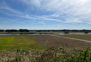 Udsigt over grønne marker, en flod og træer under en blå himmel fra Country Estate Gerner 8 i Holland.