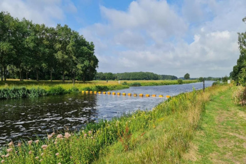 River, grassy banks, trees, and clouds near Country Estate Gerner 8 safari tent in the Netherlands.