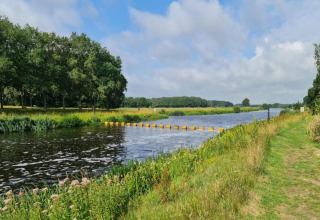 River, grassy banks, trees, and clouds near Country Estate Gerner 8 safari tent in the Netherlands.