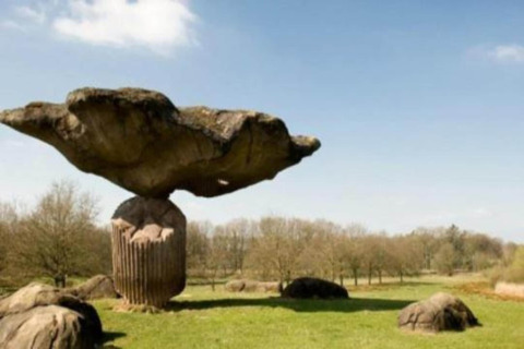 Large balanced rock shaped like a mushroom on grassy field at Country Estate Gerner 8 in the Netherlands.