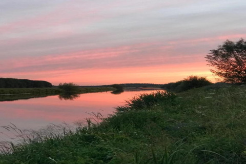 Sunset over the river at Country Estate Gerner 8 in the Netherlands, reflecting sky and lush greenery.