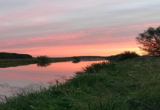 Sunset over the river at Country Estate Gerner 8 in the Netherlands, reflecting sky and lush greenery.