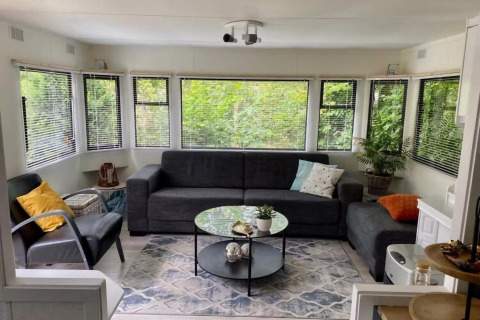 Lyst og hyggeligt opholdsområde i mobile home Sunhouse Bodhi i Holland, med store vinduer og moderne indretning.