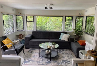 Lyst og hyggeligt opholdsområde i mobile home Sunhouse Bodhi i Holland, med store vinduer og moderne indretning.