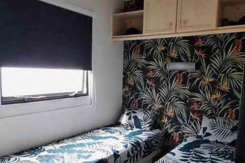 Et soveværelse i mobilhjemmet Sunhouse Bodhi i Holland med tropisk tapet og to enkeltsenge.