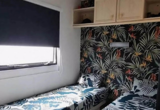 Et soveværelse i mobilhjemmet Sunhouse Bodhi i Holland med tropisk tapet og to enkeltsenge.