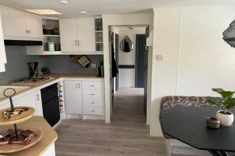 Moderne mobilhomes køkken og spiseområde, Sunhouse Bodhi i Holland, lyse hvide skabe og sort bord.