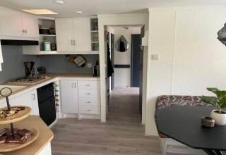 Moderne mobilhomes køkken og spiseområde, Sunhouse Bodhi i Holland, lyse hvide skabe og sort bord.