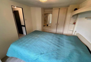 Soveværelse i mobilhome 'Sunhouse Bodhi' i Holland med dobbeltseng, skabe og spejl.