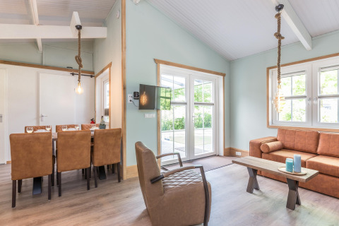 Lichte, moderne woonkamer in Residence De Eese 3 lodge in Nederland met leren bank en eettafel.