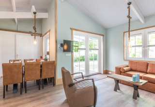 Lichte, moderne woonkamer in Residence De Eese 3 lodge in Nederland met leren bank en eettafel.