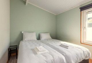 Slaapkamer bij Residence De Eese 3 met twee aparte bedden, wit linnengoed en zonlicht door het raam.