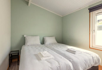 Schlafzimmer in der Residence De Eese 3 mit zwei Einzelbetten, weißer Bettwäsche und Tageslichtfenster.