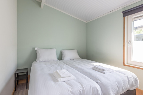 Slaapkamer in Residence De Eese 3 met twee eenpersoonsbedden, wit beddengoed en raam met licht.