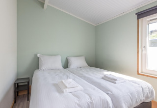 Slaapkamer in Residence De Eese 3 met twee eenpersoonsbedden, wit beddengoed en raam met licht.